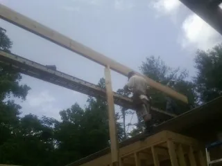 Carpenter setting a ridge beam over a new addition frame — Ice Dam Removal by Roofing Brothers in Alleman