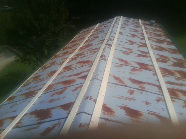 Rusted metal roof panels with new wood purlins before replacement — Storm Damage Roof Repair in Alleman by Roofing Brothers