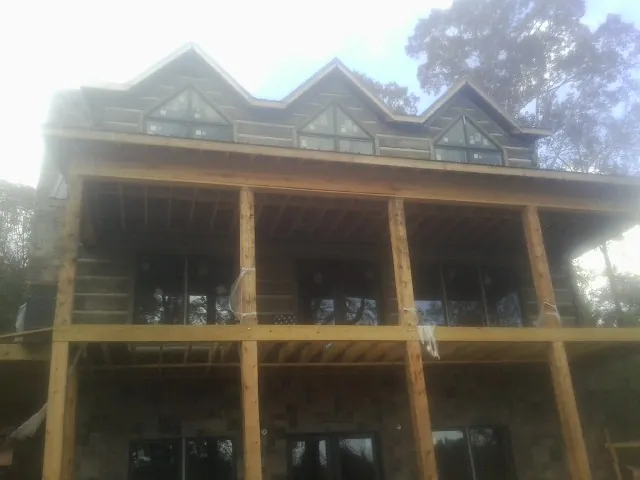 Dormers and porch framing on a large log home under construction — Roof Coating work by our crew in Alleman
