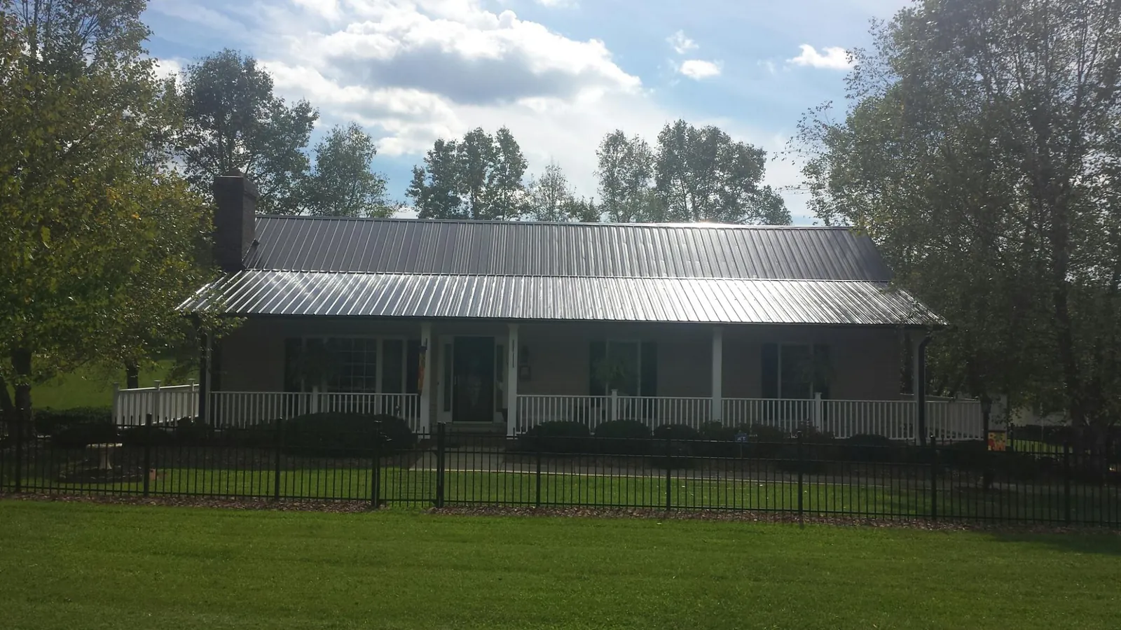 Gray metal roof on a brick ranch with a full width front porch — Gutter Guard Installation work by our crew in Alleman