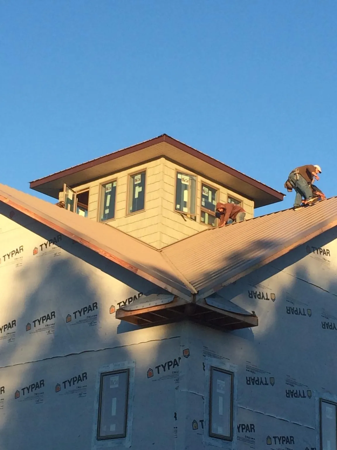 Roofers working around a rooftop cupola on a new metal roof at sunset — Roof Waterproofing in Alleman by Roofing Brothers